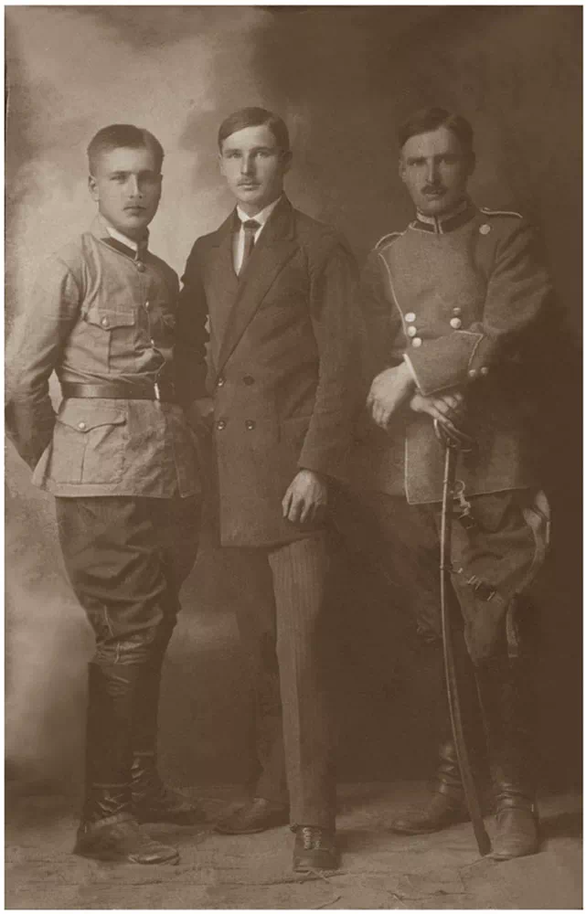 mężczyzna w garniturze i dwóch mężczyzn w mundurach